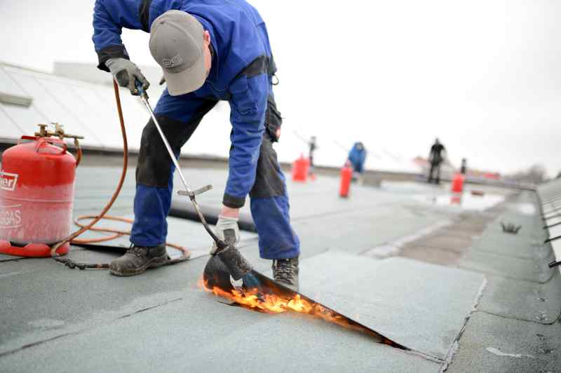 Commercial roofing company doing repairs on a single-ply roof membrane with a torch in Lake Ozark, MO