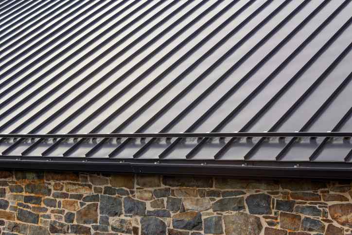 Standing seam modern metal roof over vintage stone wall